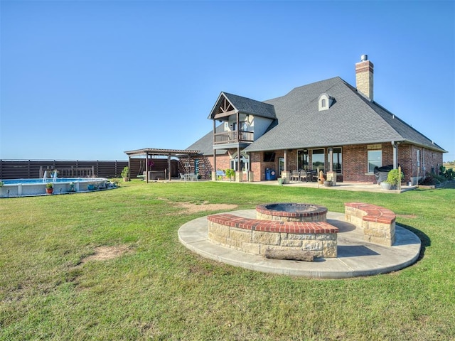 back of house with a fenced in pool, a yard, a balcony, and an outdoor fire pit