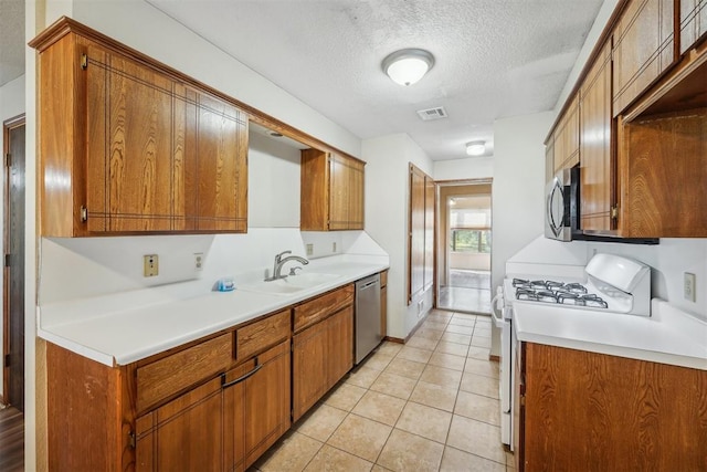 kitchen with sink, light tile patterned floors, a textured ceiling, and appliances with stainless steel finishes