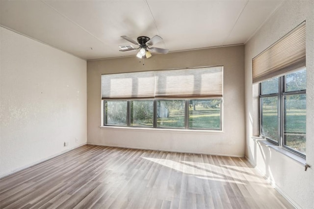 empty room featuring plenty of natural light, ceiling fan, and light wood-type flooring