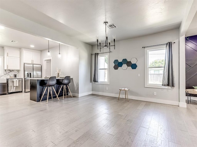 kitchen with decorative light fixtures, a healthy amount of sunlight, white cabinetry, and appliances with stainless steel finishes