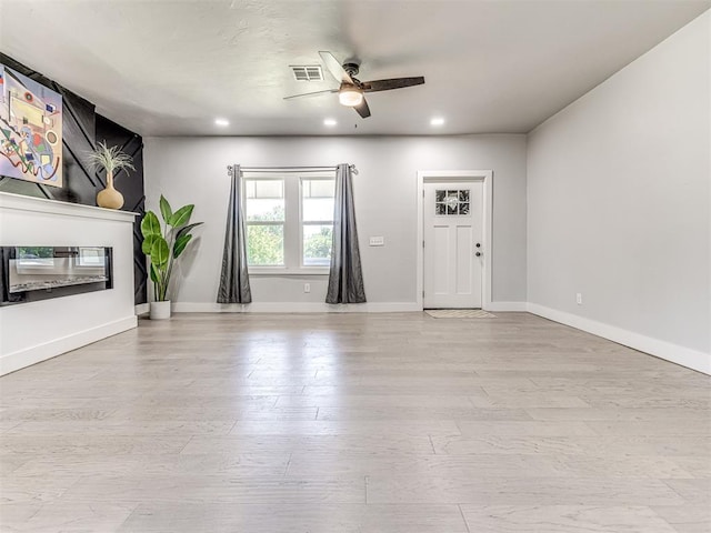 unfurnished living room with ceiling fan and light wood-type flooring