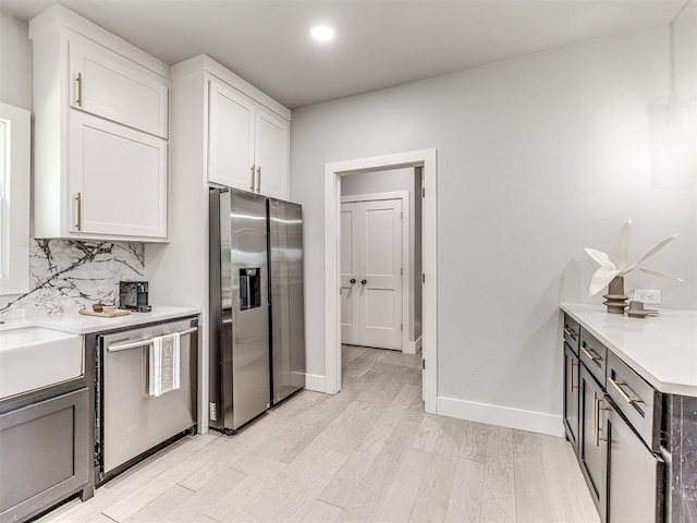 kitchen featuring stainless steel appliances, white cabinetry, tasteful backsplash, and light hardwood / wood-style flooring