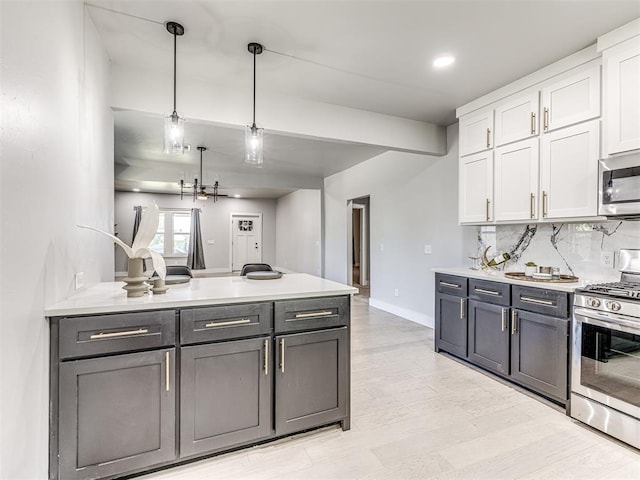 kitchen with appliances with stainless steel finishes, light wood-type flooring, tasteful backsplash, pendant lighting, and white cabinets