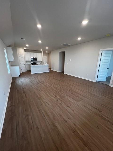 unfurnished living room with visible vents, baseboards, dark wood finished floors, and recessed lighting