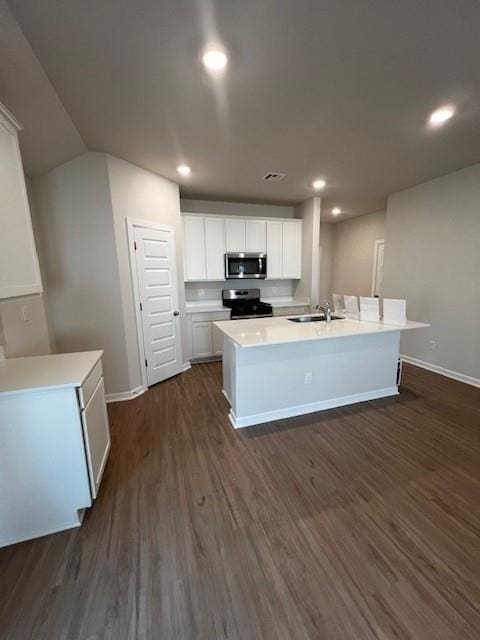 kitchen with appliances with stainless steel finishes, light countertops, white cabinets, and an island with sink