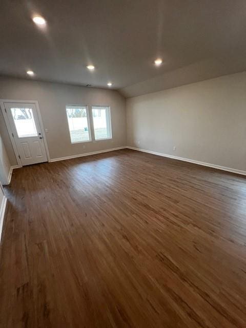 spare room featuring lofted ceiling, dark hardwood / wood-style flooring, and a wealth of natural light