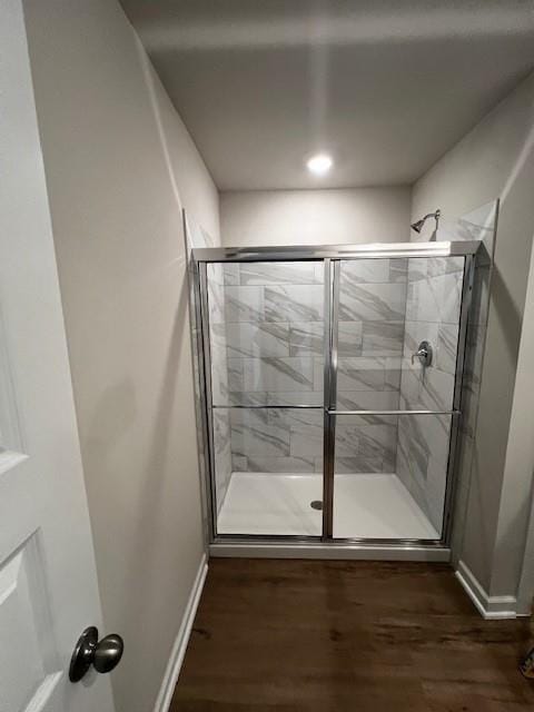 full bathroom with a stall shower, baseboards, and wood finished floors