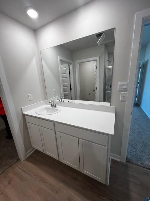 bathroom with a shower with shower door, baseboards, wood finished floors, and vanity