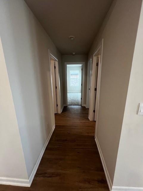 hallway with dark wood-style flooring and baseboards