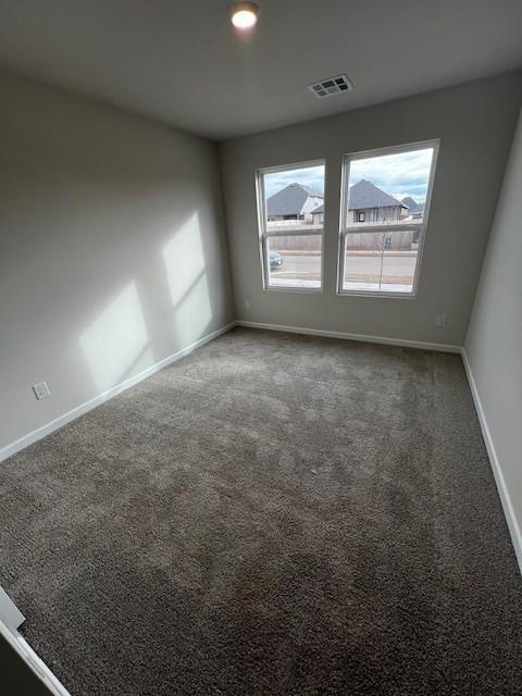 spare room featuring dark colored carpet