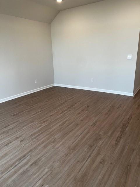 empty room with dark wood-type flooring and lofted ceiling