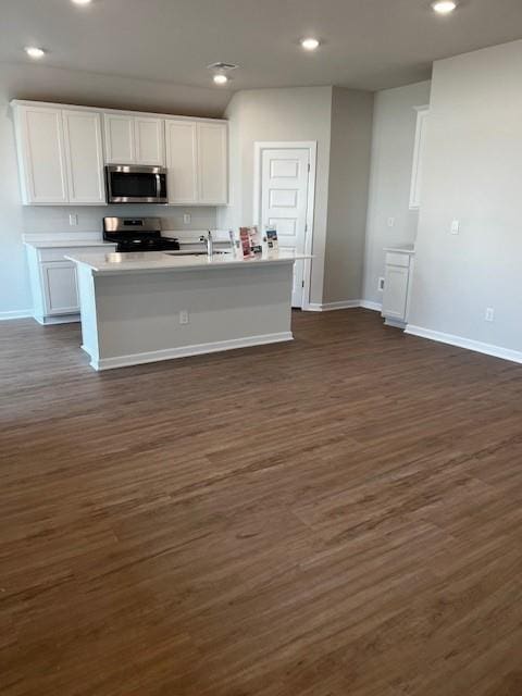 kitchen featuring dark wood-type flooring, sink, white cabinetry, a center island with sink, and appliances with stainless steel finishes