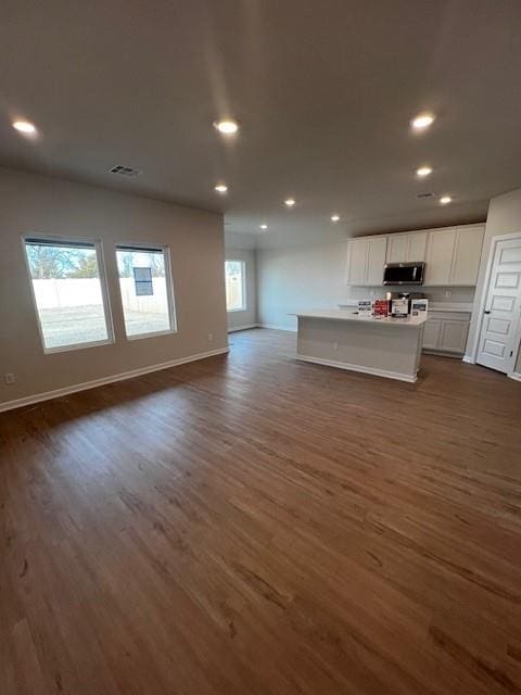 kitchen with white cabinetry, dark hardwood / wood-style flooring, and a center island with sink