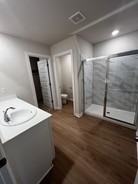 bathroom with vanity, hardwood / wood-style flooring, toilet, and walk in shower