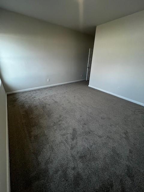 unfurnished room featuring dark colored carpet