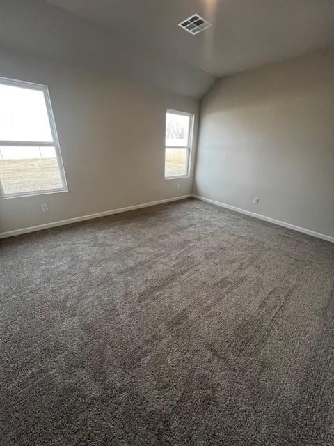 empty room with lofted ceiling and dark carpet