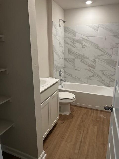 full bathroom featuring vanity, hardwood / wood-style floors, tiled shower / bath combo, and toilet