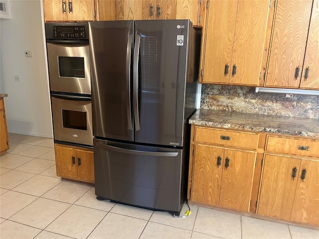 kitchen with decorative backsplash, light tile patterned floors, and stainless steel appliances