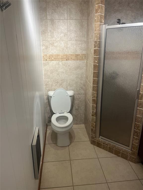 bathroom featuring tile patterned flooring, a shower with shower door, and toilet