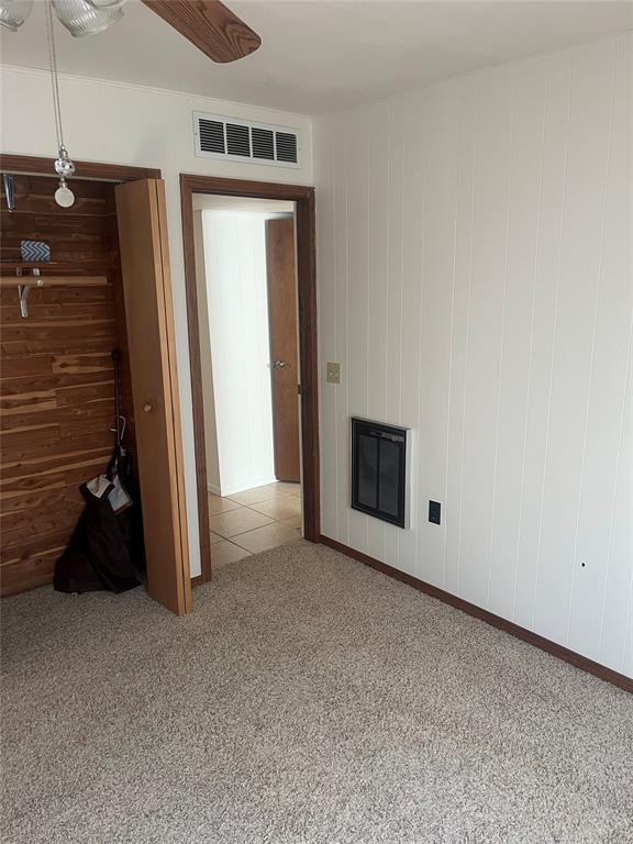 carpeted spare room featuring ceiling fan and wooden walls