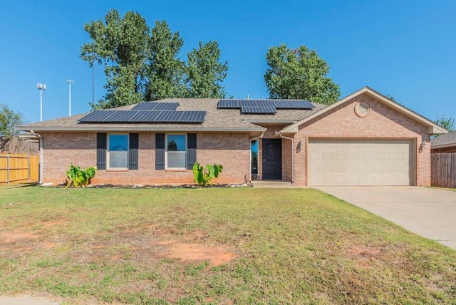 ranch-style home featuring solar panels, a garage, and a front yard