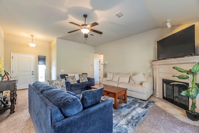 living room with ceiling fan, light colored carpet, and a tiled fireplace