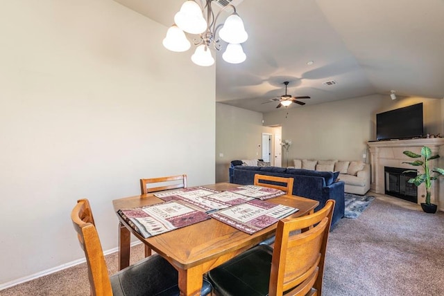 dining space featuring carpet, ceiling fan with notable chandelier, and vaulted ceiling