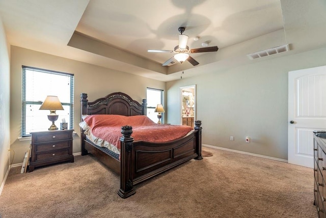 carpeted bedroom featuring a tray ceiling and ceiling fan