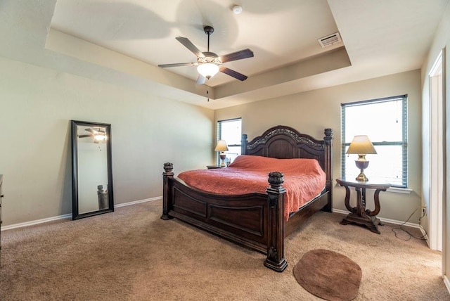 bedroom featuring ceiling fan, light carpet, and a tray ceiling