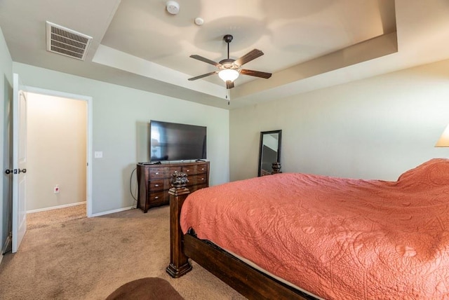 bedroom with light carpet, a tray ceiling, and ceiling fan