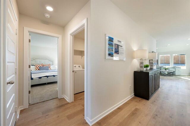 corridor with light wood-style floors, baseboards, washer / clothes dryer, and recessed lighting