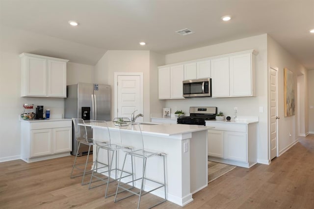 kitchen featuring visible vents, white cabinetry, light countertops, appliances with stainless steel finishes, and an island with sink