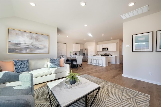 living room featuring light wood-style flooring, visible vents, baseboards, and recessed lighting