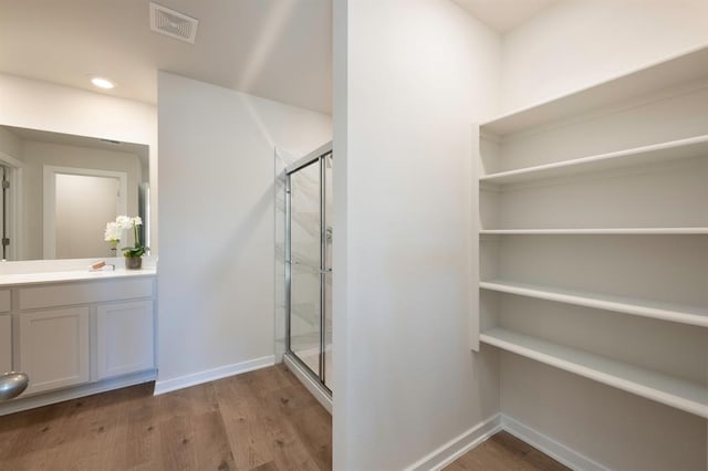 full bath with a stall shower, baseboards, visible vents, and wood finished floors