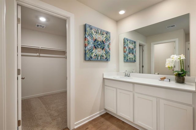 bathroom featuring baseboards, a spacious closet, visible vents, and vanity