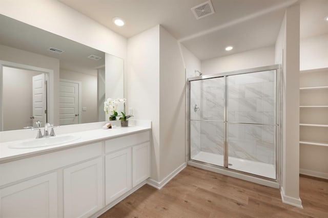 bathroom with vanity, wood finished floors, visible vents, and a shower stall