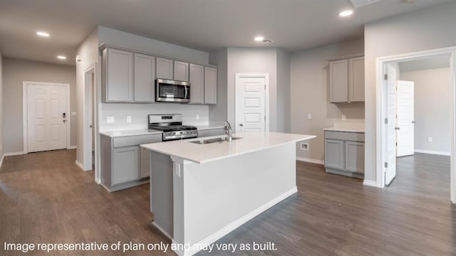 kitchen with light countertops, appliances with stainless steel finishes, an island with sink, and gray cabinetry