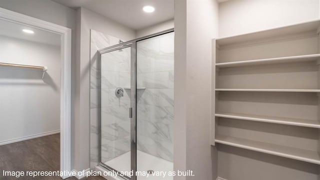 full bathroom with a stall shower, a walk in closet, wood finished floors, and recessed lighting