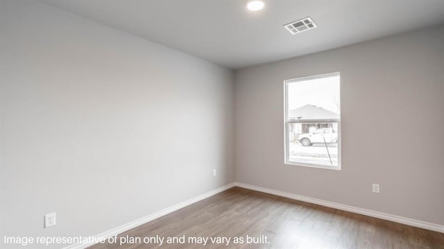 spare room featuring baseboards, visible vents, and wood finished floors