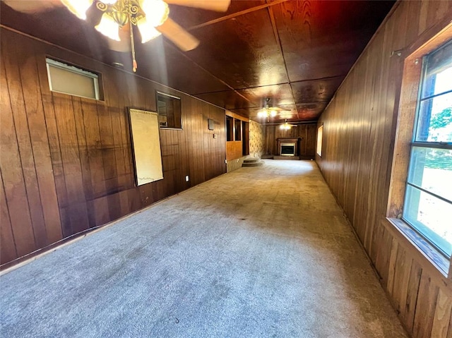 carpeted spare room featuring ceiling fan and wooden walls