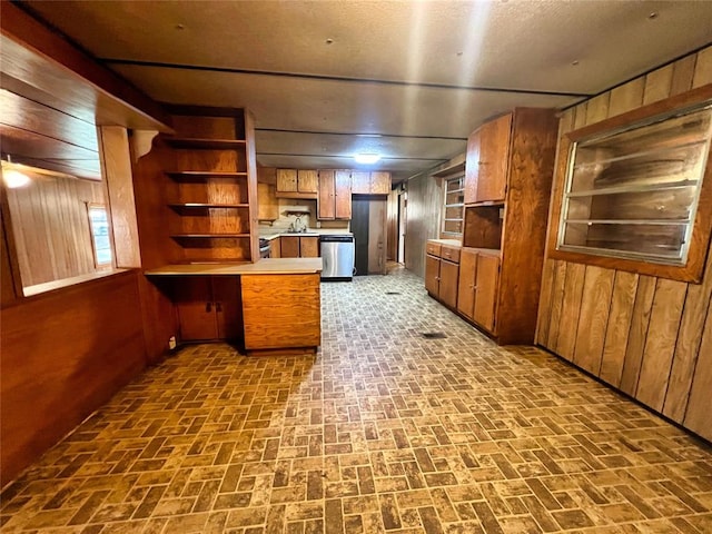 kitchen with dishwasher, built in features, kitchen peninsula, and wooden walls