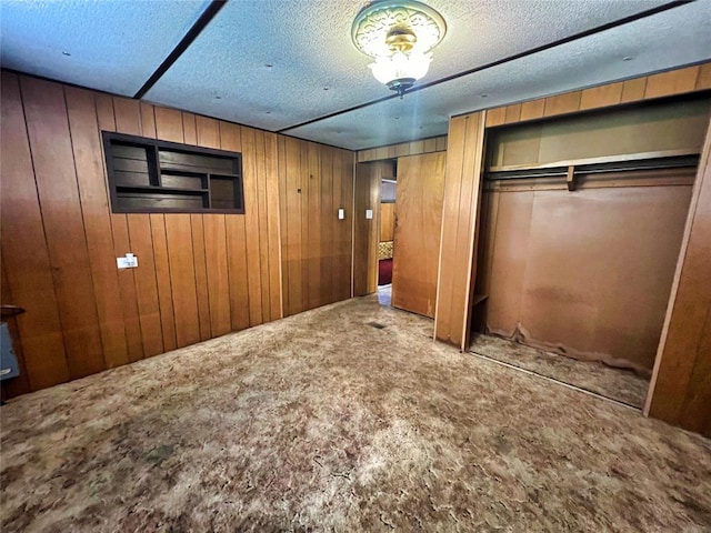 unfurnished bedroom with carpet flooring, wood walls, and a textured ceiling