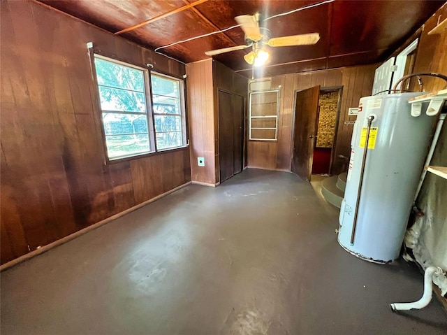 basement featuring gas water heater, ceiling fan, and wooden walls