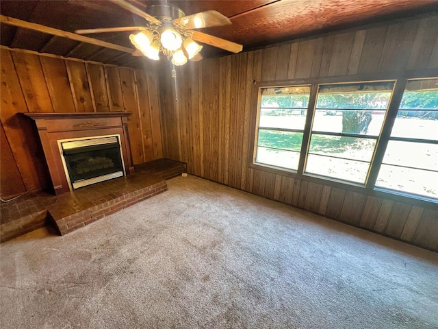 unfurnished living room featuring carpet flooring, a fireplace, plenty of natural light, and wooden walls