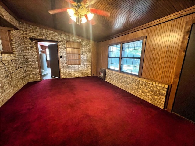 carpeted spare room featuring ceiling fan, wood ceiling, brick wall, and heating unit