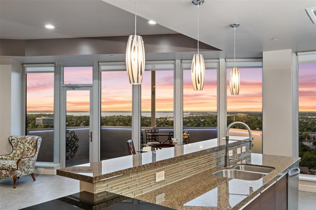 kitchen with concrete floors, stone countertops, hanging light fixtures, and sink