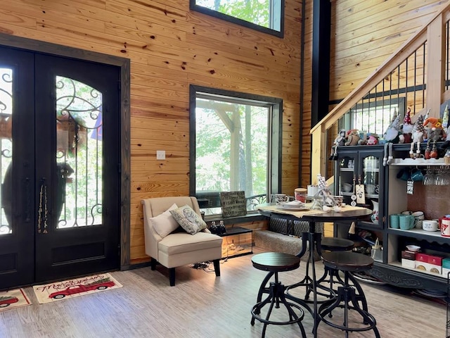 foyer entrance with hardwood / wood-style floors, french doors, wooden walls, and a high ceiling