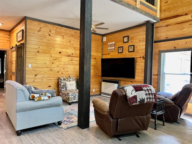 living room with ceiling fan, wood walls, and wood-type flooring