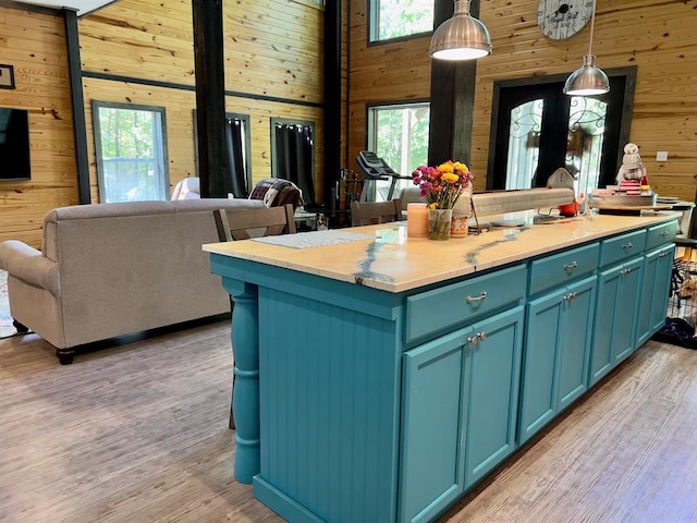kitchen featuring a healthy amount of sunlight, a kitchen island with sink, and wooden walls