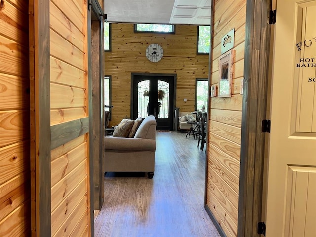 corridor featuring hardwood / wood-style flooring, wood walls, a barn door, and a towering ceiling
